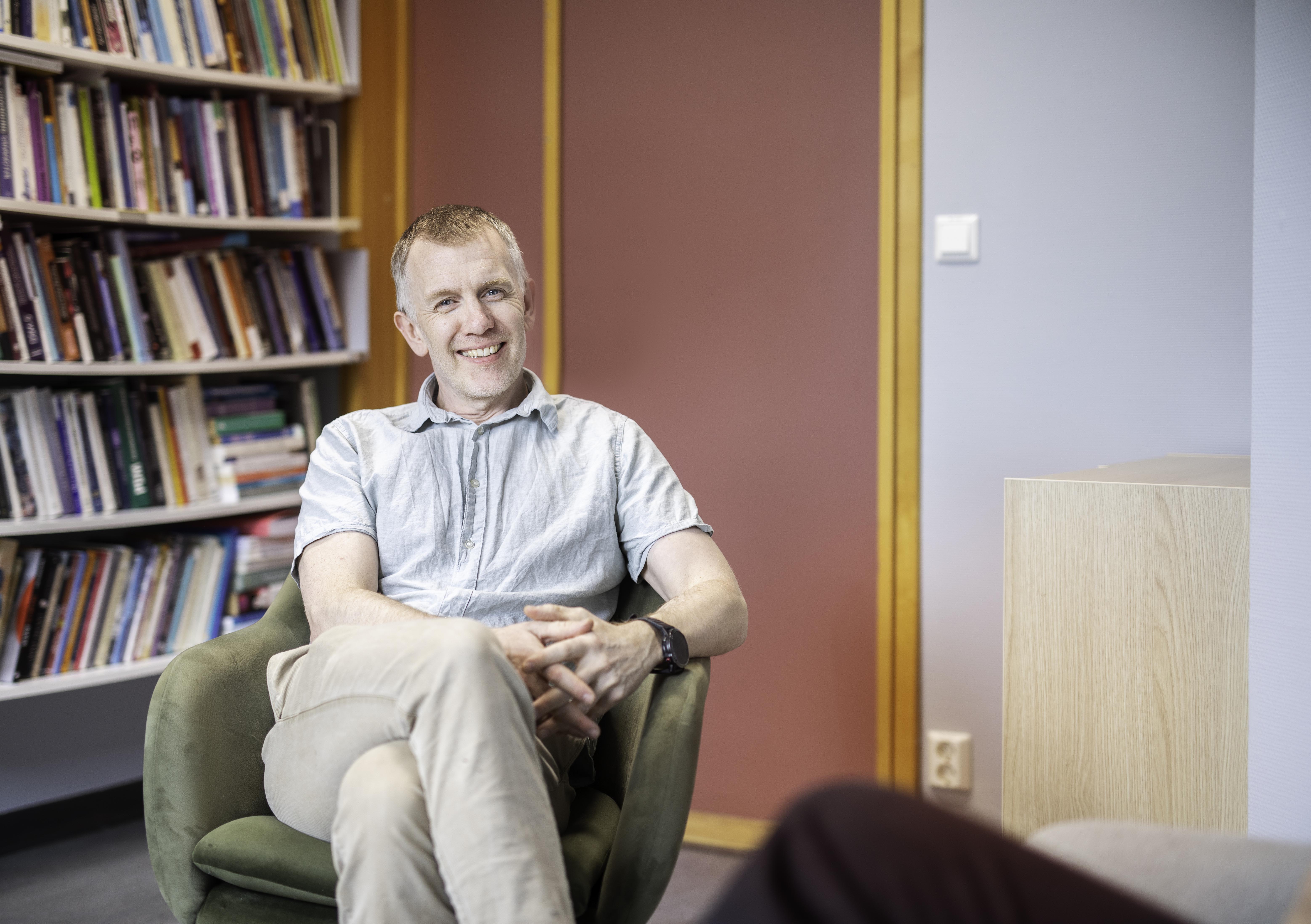 Christian Moltu sit i ein sofa, ser mot kamera og smiler.